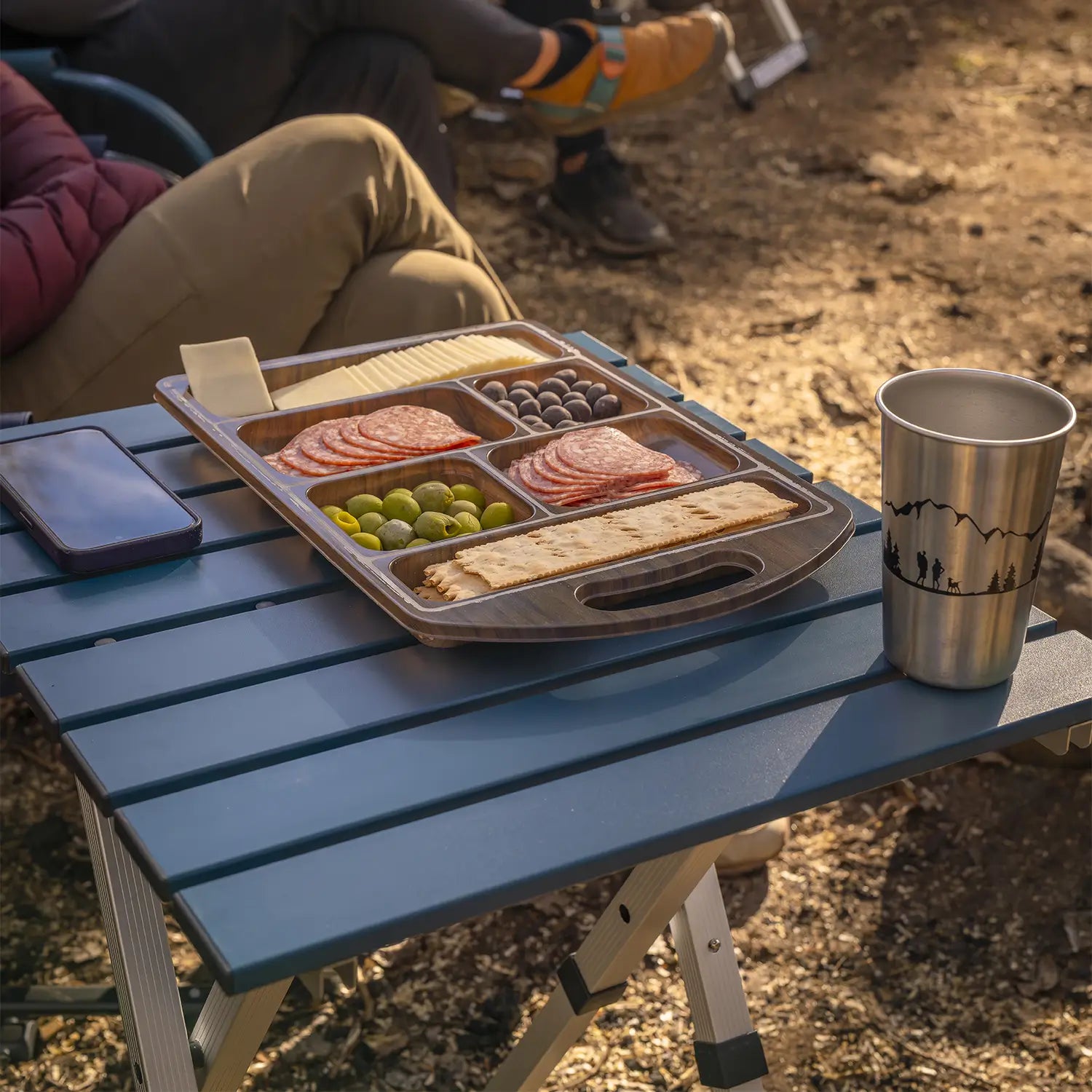 A charcuterie tray resting on a teal Compact Camp Table. 