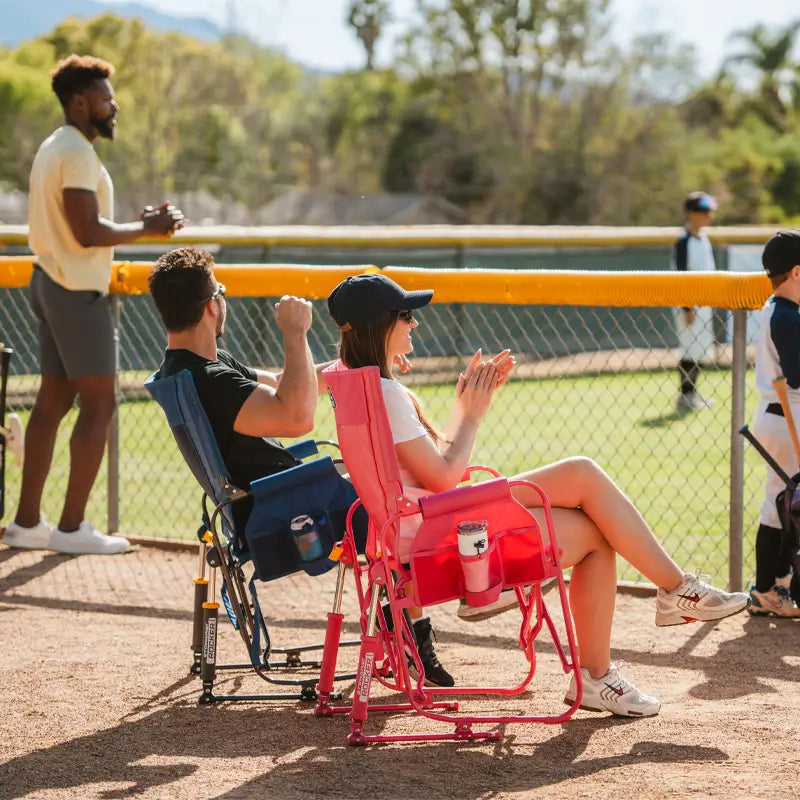Man and woman cheering from the sidelines, seated in bright pink and navy Stowaway Rockers.