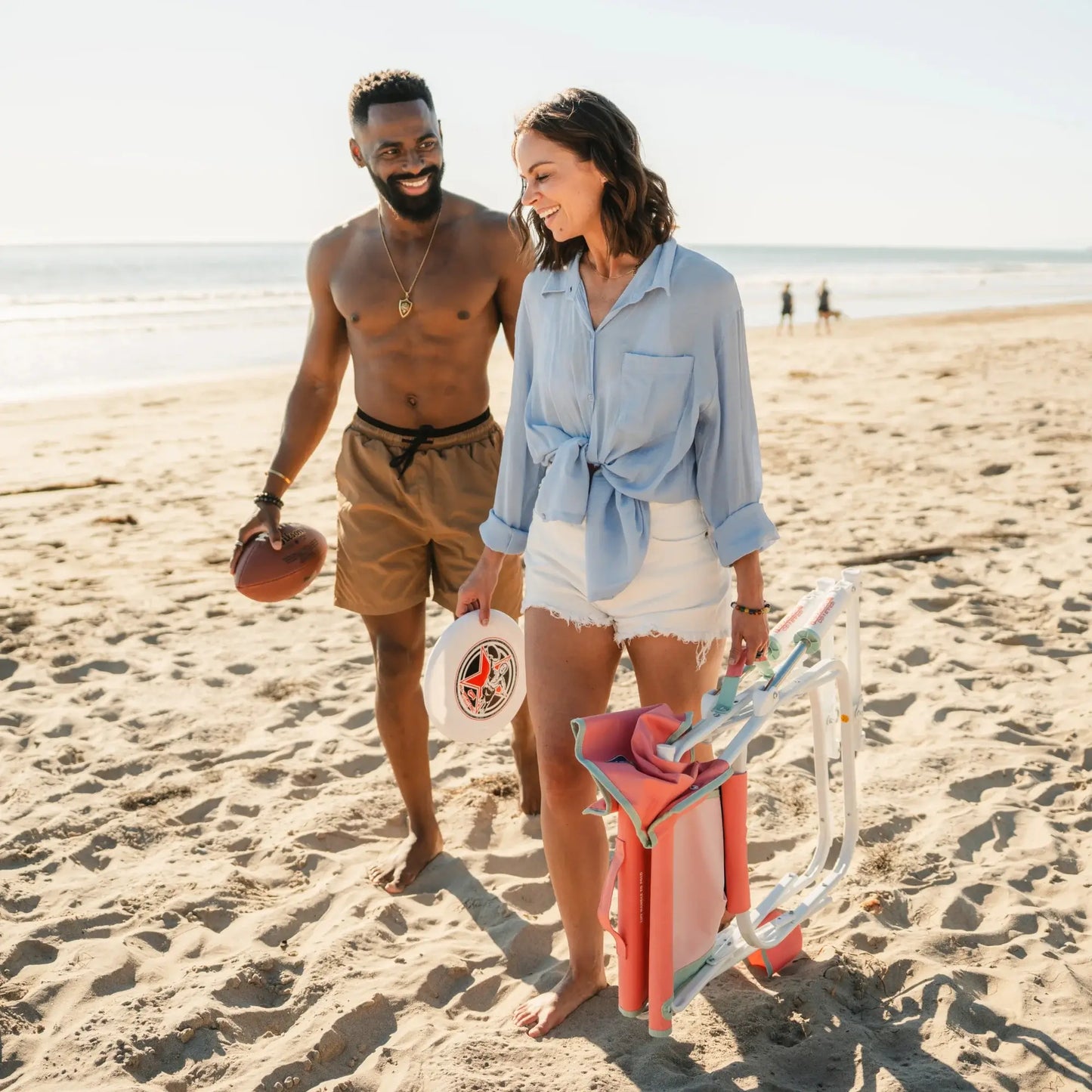 A man and woman walking together on a beach while the woman carries a Grab and Go Rocker. 